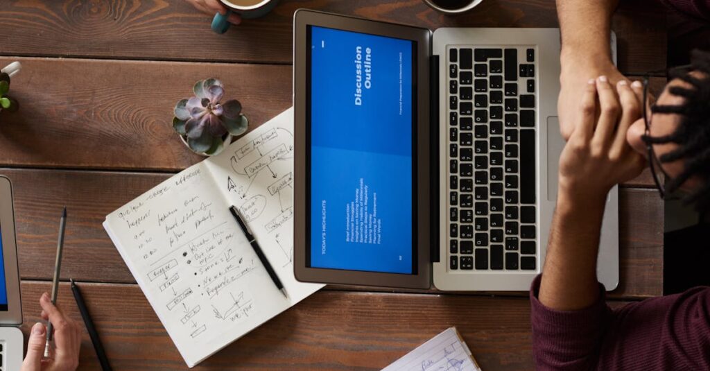 Group of coworkers discussing business strategies with laptops and tablets in a modern office setting.